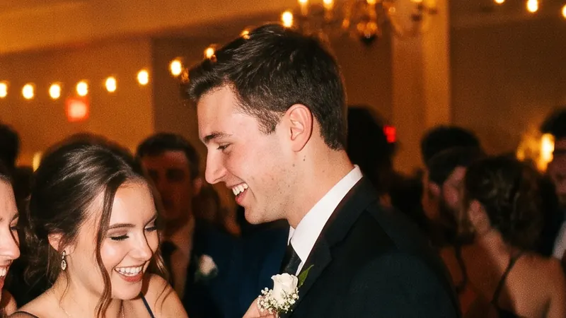 A young woman in a navy gown pins a white boutonniere on her date’s lapel on a crowded dance floor
